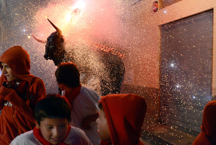 Revellers are showered with sparks from the "Fire Bull", a man carrying a metal structure loaded with fireworks on the fourth day of the San Fermin festival in Pamplona July 9, 2012. Visitors to the nine day festival, depicted in Ernest Hemingway's 1926 n