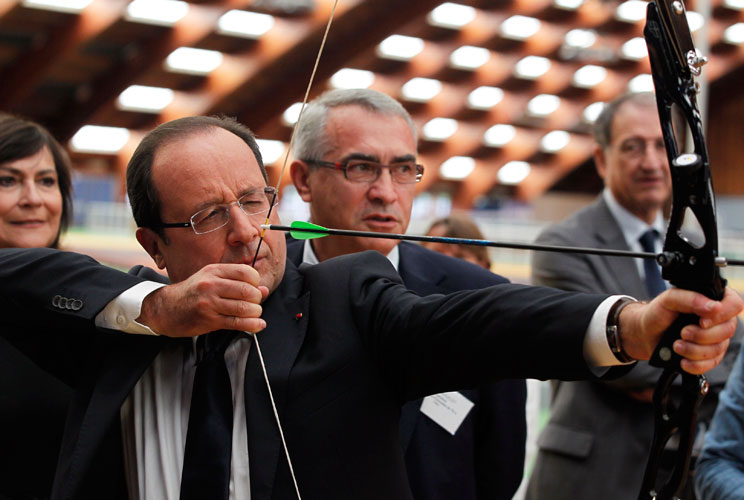 France's President Francois Hollande (L) prepares to shoot an arrow during a visit to meet members of the French team for the London Olympics 2012 at the training headquarters of INSEP (National Institute for Sport and Physical Education) in Paris July 16