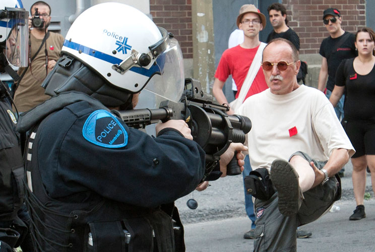 A riot policeman aims his tear gas gun at a protester during a march against student tuition hikes and Bill 78 in downtown Montreal, Quebec July 22, 2012. The mass demonstration, which is quickly becoming a monthly protest in Montreal since it started aro