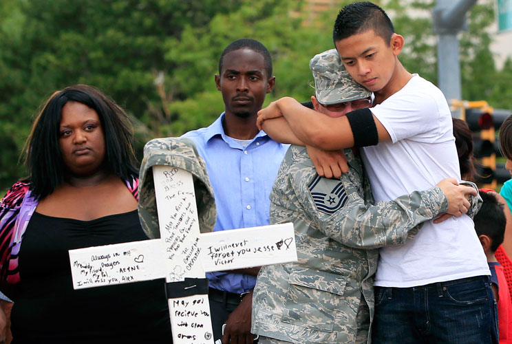 People grieve at a memorial for victims behind the theater where a gunman opened fire on moviegoers in Aurora, Colorado July 22, 2012. Residents of a Denver suburb mourned their dead on Sunday from a shooting rampage by a "demonic" gunman who killed 12 pe