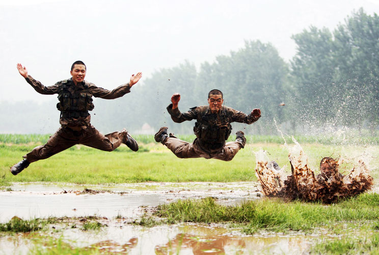 Soldiers jump as they take part during a military training session in muddy water at a military base in Jinan, Shandong province, July 23, 2012. 