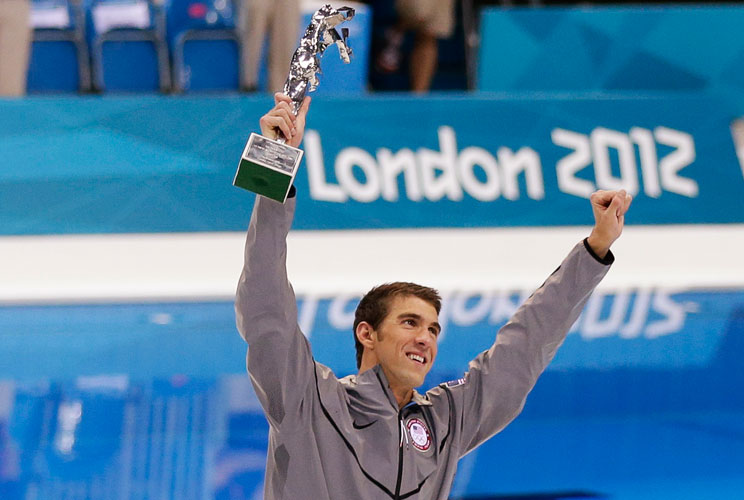 Michael Phelps of the U.S. celebrates with his trophy awarded to him by FINA honouring him as the most decorated Olympian of all time, after winning the men's 4x100m medley relay final during the London 2012 Olympic Games at the Aquatics Centre August 4, 