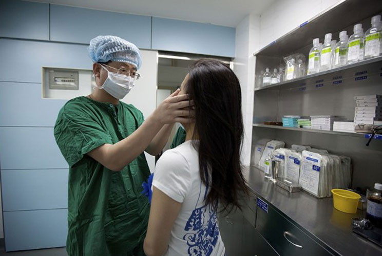 As China increases in wealth, more people are turning to luxuries such as cosmetic surgery. In the photo, Li Yujie inspects a patient after performing an operation to enlarge her nose at Shenzhen Humanity Hospital.