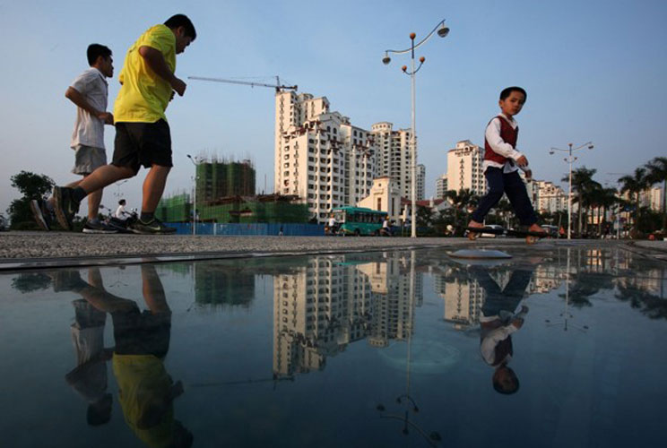 People pass a development of luxury housing in the southern Chinese city of Qionghai.