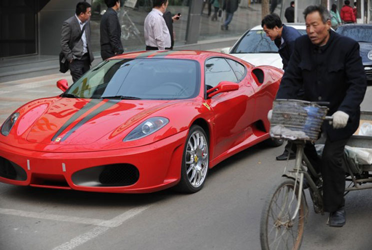 A cyclist rides by a Ferrari on a street in Beijing, a sign of China's stunning economic transformation and a ticking time bomb at the heart of the Communist Party's plan to revamp the economy.