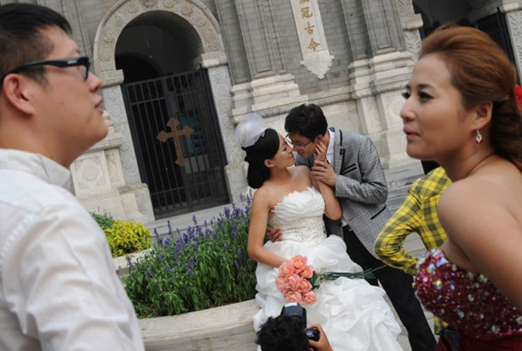 An affluent Chinese couple pose for their wedding photos outside the Wangfujing Church in Beijing.