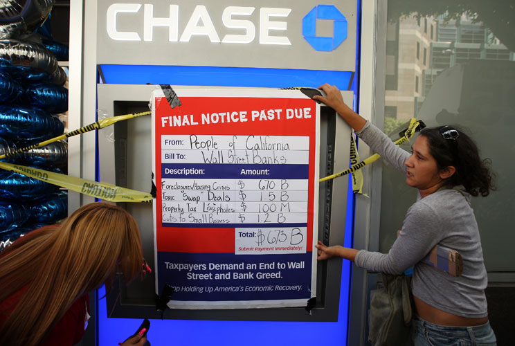 Protesters hang a mock past due notice over an automated teller machine at a Chase Bank building on October 6, 2011 in Los Angeles, California. The demonstrators marched to major bank offices to protest the role of Wall Street banks in the federal budget 