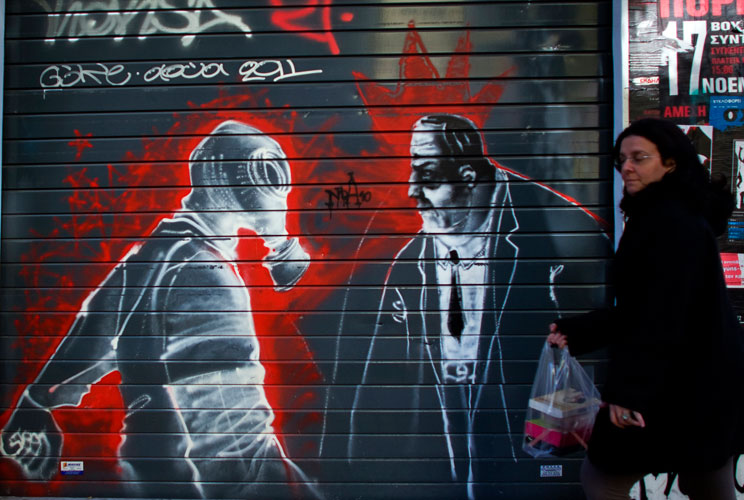 A woman walks past graffiti displayed on a building on December 6, 2011 in Athens, Greece. Graffiti artists throughout the city are expressing the effects of austerity measures that have plagued the community as Greece continues to struggle in debt while 