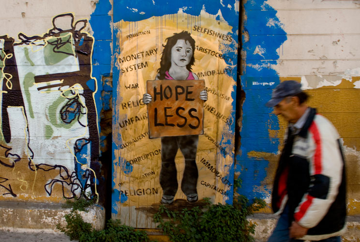 A man walks past graffiti displayed on a building on December 6, 2011 in Athens, Greece. Graffiti artists throughout the city are expressing the effects of austerity measures that have plagued the community as Greece continues to struggle in debt while la