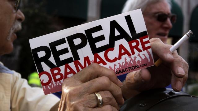 File photo of a demonstrator holding a pamphlet outside a "Defund Obamacare Tour" rally in Indianapolis