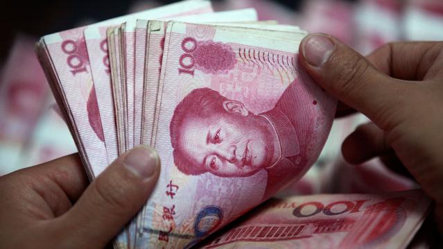 Bank clerk counts Chinese yuan banknotes at a branch of Industrial and Commercial Bank of China in Huaibei