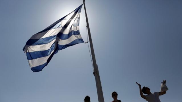 FILE PHOTO - Tourists stand under a Greek national flag atop the Acropolis hill in Athens, June 14, 2015.   REUTERS/Kostas Tsironis 