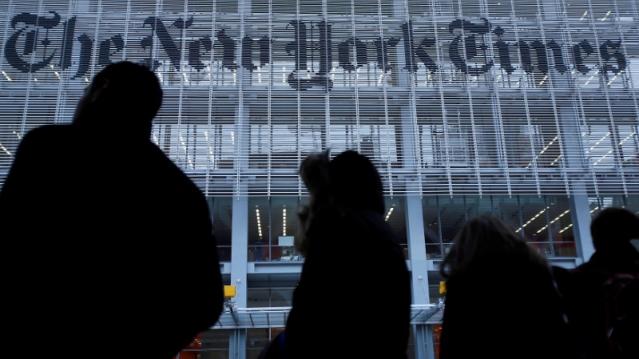 FILE PHOTO: People line up for taxi across the street from the New York Times head office in New York