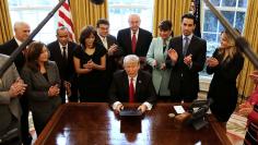 U.S. President Donald Trump signs an executive order cutting regulations, accompanied by small business leaders at the Oval Office of the White House in Washington U.S.