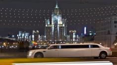 Cars drive past sightseers on a bridge over the Moskva river near a Stalin era skyscraper in central Moscow