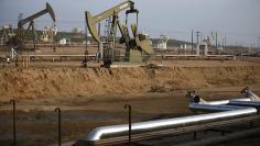 Pump jacks and pipes are seen on an oil field near Bakersfield on a foggy day, California