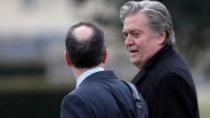 White House Chief Strategist Steve Bannon talks with Chief of Staff Reince Priebus as they depart the White House in Washington