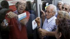 Pensioners waiting outside a closed National Bank branch and hoping to get their pensions, argue with a bank employee in Iraklio on the island of Crete