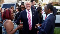 Republican presidential nominee Donald Trump (C) speaks with homeowner Felicia Reese (L) and Ben Carson in front of Carson's childhood home in Detroit