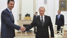 File photo of Russian President Putin shaking hands with Syrian President Assad during a meeting at the Kremlin in Moscow