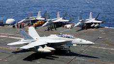 U.S. Navy personnel watch an F18 fighter jet lands on the deck of aircraft carrier USS Carl Vinson in South China Sea
