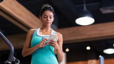 Woman using smartphone in fitness gym