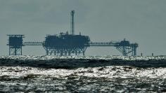 An oil and gas drilling platform stands offshore as waves churned from Tropical Storm Karen come ashore in Dauphin Island, Alabama