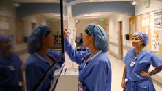 Operating room Charge Nurse Bridgett Pacheco writes on the daily O.R. schedule as O.R. Technician Liz Keating watches at Littleton Adventist Hospital, part of Centura Health in Littleton