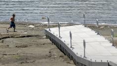 A boy plays near a dock at Seaport Boat Launch that rests on a portion of dried up lake bed at Lake Elsinore in Lake Elsinore, California