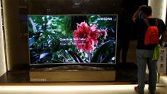 A man stands next to a Samsung Electronics "Quantum Dot" SUHD television at its headquarters in Seoul