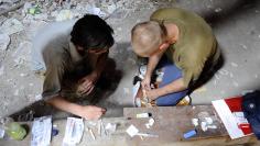 Men prepare to inject heroin at an abandoned house in Ljubljana