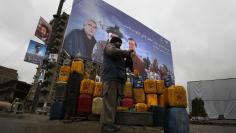 Petrol vendor prepares his roadside stall in front of an election advertisement for presidential candidate Ashraf Ghani in Kabul