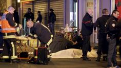 General view of the scene that shows rescue services personnel working near the covered bodies outside a restaurant following a shooting incident in Paris