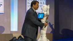 Astrophysicist Neil deGrasse Tyson greets Pepper, a social humanoid robot developed by Aldebaran for SoftBank, on stage during the Clinton Global Initiative's annual meeting in New York