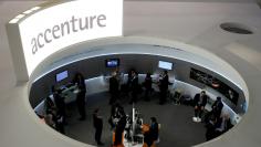 FILE PHOTO: Visitors look at devices at Accenture stand at the Mobile World Congress in Barcelona, February 26, 2013.    REUTERS/Albert Gea/File Photo                       