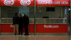 People stand in front of an empty Niki customer care desk at Palma de Mallorca airport