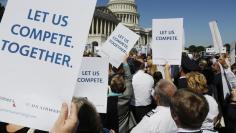 US Airways pilots hold signs as pilots, flight attendants, baggage handlers and other union members working for American Airlines and US Airways demonstrate urging the U.S. Justice Department to allow the two companies to merge at a rally in front of the 