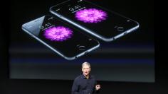 FILE PHOTO: Apple CEO Tim Cook stands in front of a screen displaying the IPhone 6 during a presentation at Apple headquarters in Cupertino, California October 16, 2014.  REUTERS/Robert Galbraith/File Photo