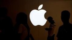 FILE PHOTO: A man looks at the screen of his mobile phone in front of an Apple logo outside its store in Shanghai, China on July 30, 2017.   REUTERS/Aly Song/File Photo