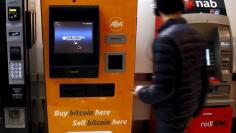 A customer of an Australian bank walks away after withdrawing money from an Automatic Teller Machine (ATM) located next to a Bitcoin ATM at a shopping mall in central Sydney, Australia, October 1, 2015.  Picture taken October 1, 2015. REUTERS/David Gray