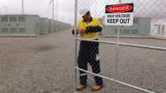 A worker checks the main gate for the compound housing the Hornsdale Power Reserve, featuring the world's largest lithium ion battery made by Tesla, during the official launch near the South Australian town of Jamestown, in Australia, December 1, 2017.  