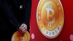 An attendant holds a bitcoin sign during the opening of Hong Kong's first bitcoin retail store February 28, 2014. REUTERS/Bobby Yip/File Photo 