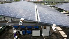 An Electrify SG engineer shows how a powerport is installed to record data of photovoltaic solar panels on a rooftop in Singapore