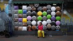 FILE PHOTO: A woman sits in front of a shop selling stools after buying one in the Bras neighborhood of Sao Paulo August 9, 2013. REUTERS/Nacho Doce/File Photo          