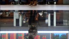 A woman is reflected on the floor as she looks at an electronic board showing the graph of the recent fluctuations of market indices at the floor of Brazil's BM&F Bovespa Stock Market in downtown Sao Paulo