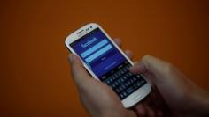 A smartphone user logs into his Facebook account in Rio de Janeiro