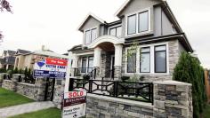 FILE PHOTO: Realtor signs are hung outside a newly sold property in a Vancouver neighborhood