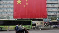 Residents ride their electric scooter past a giant Chinese national flag to mark the 65th anniversary of the founding of the People's Republic of China, in Zhengzhou, Henan province October 1, 2014. REUTERS/Stringer 