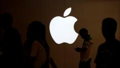 A man looks at the screen of his mobile phone in front of an Apple logo outside its store in Shanghai, China July 30, 2017. REUTERS/Aly Song