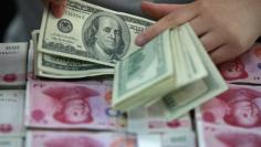 A bank clerk counts U.S. dollar banknotes on bundles of 100 Chinese yuan banknotes at a branch of a bank in Huaibei, Anhui province April 26, 2012. REUTERS/Stringer